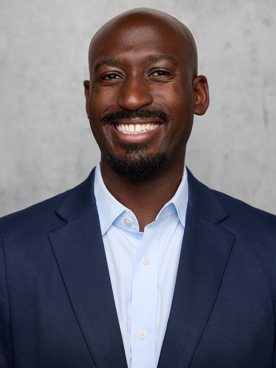 Smiling man in scrubs with glasses.