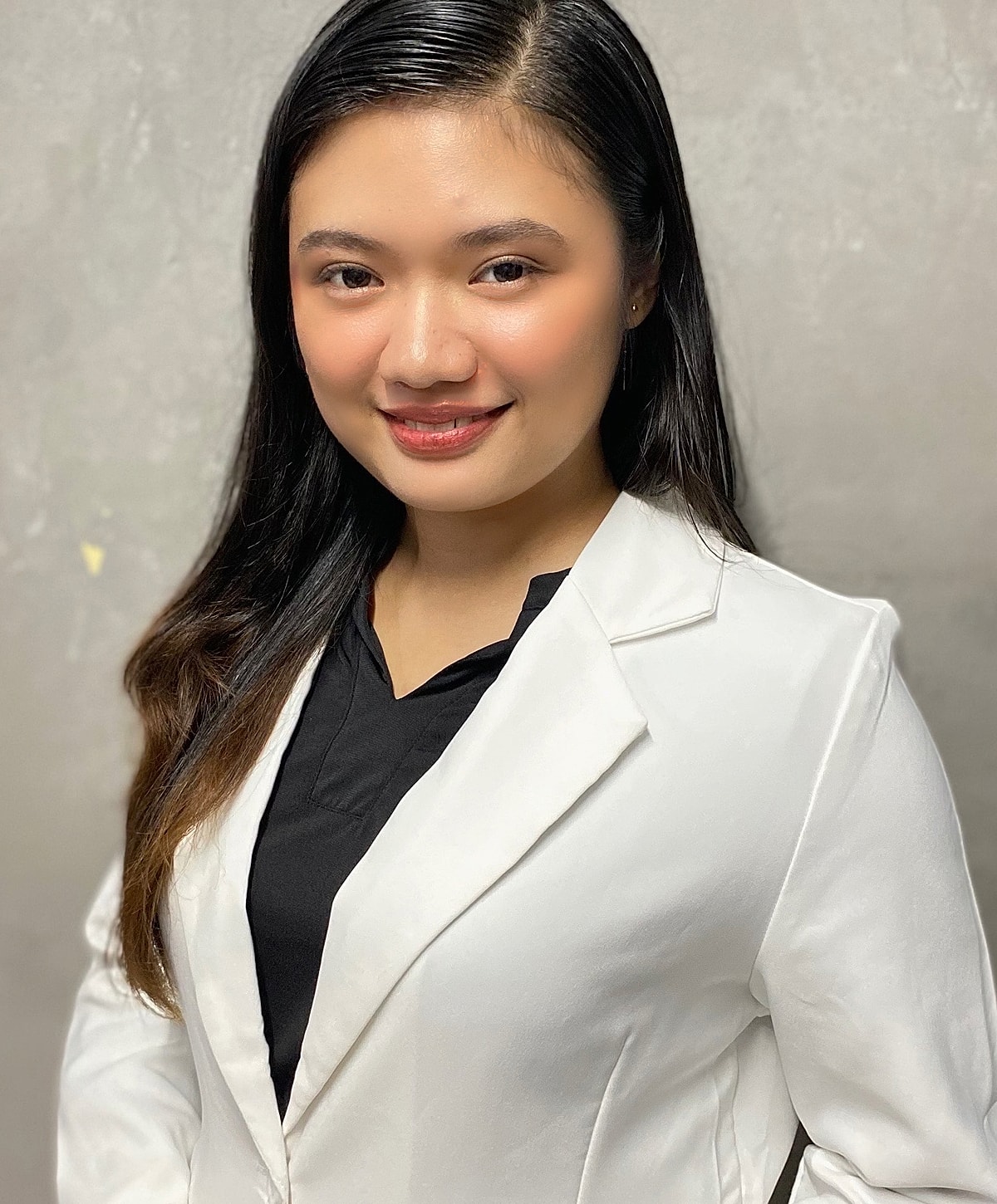 Woman in a white blazer smiling confidently.