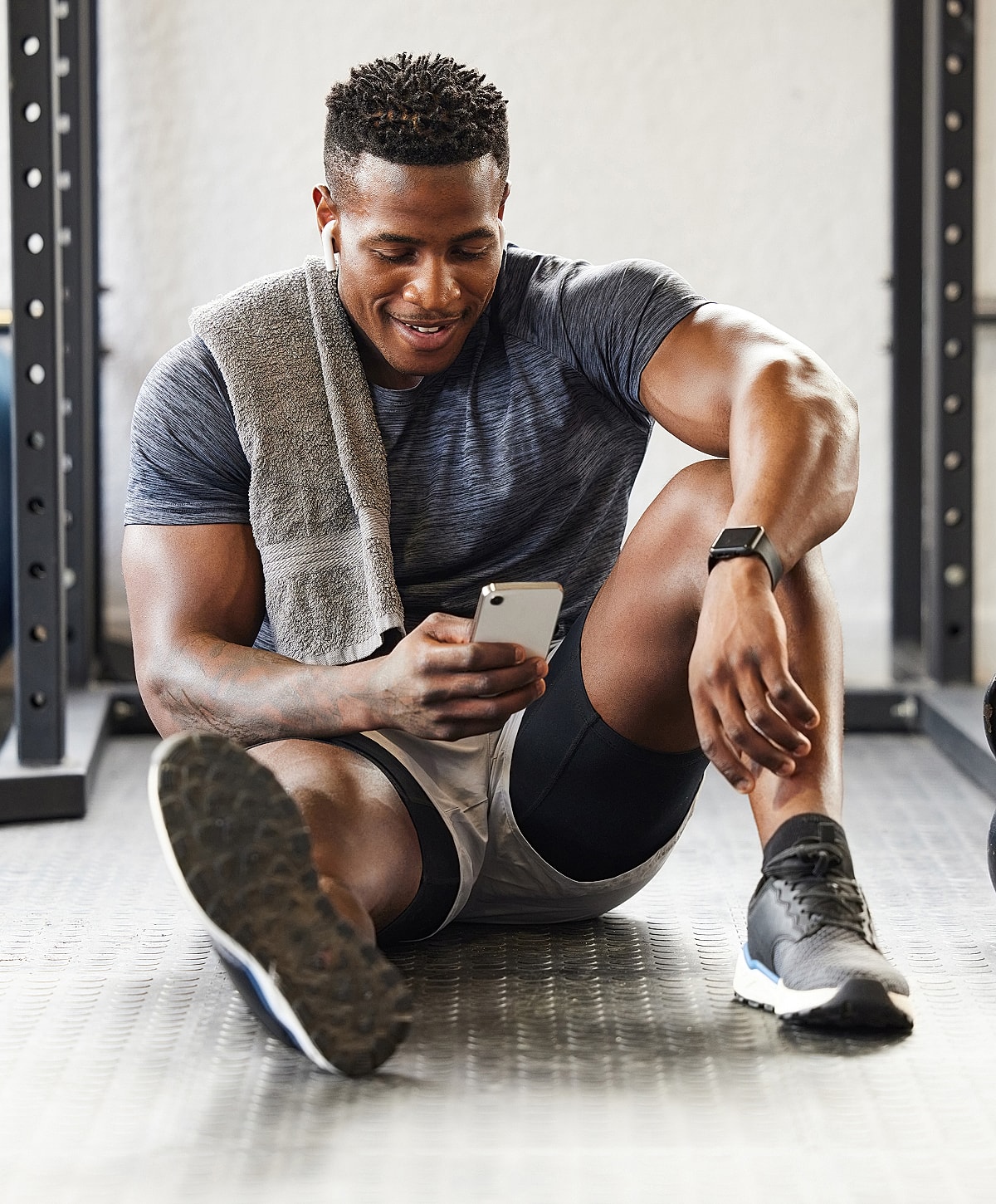 Man resting in gym, checking his phone.