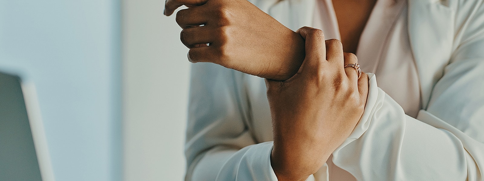Hands adjusting clothing with rings on fingers.