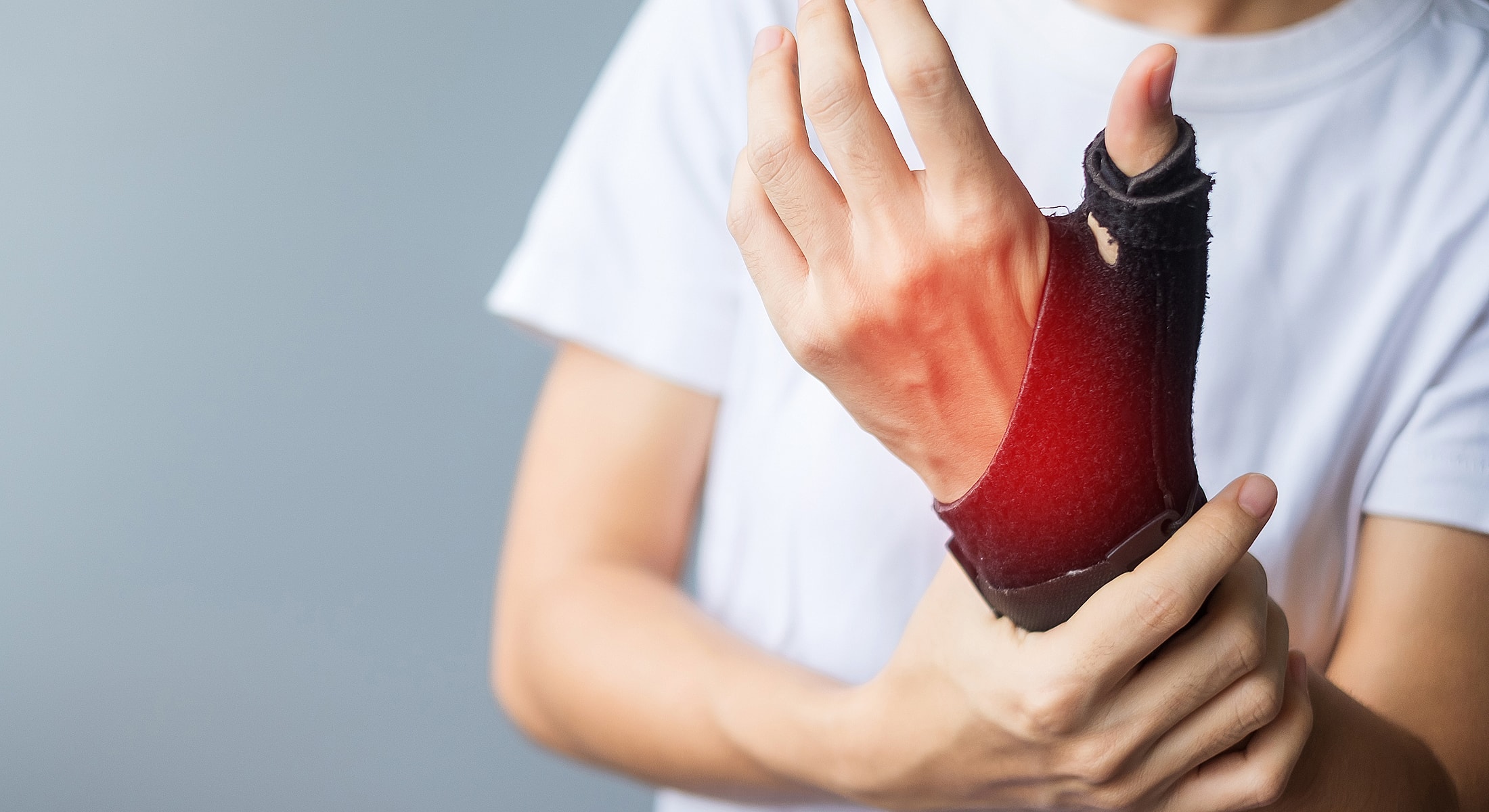 Person wearing wrist support, showing discomfort.