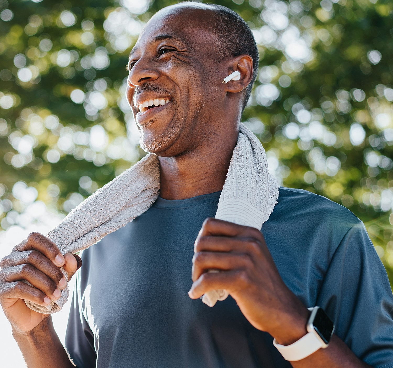 Smiling man in workout attire with towel.